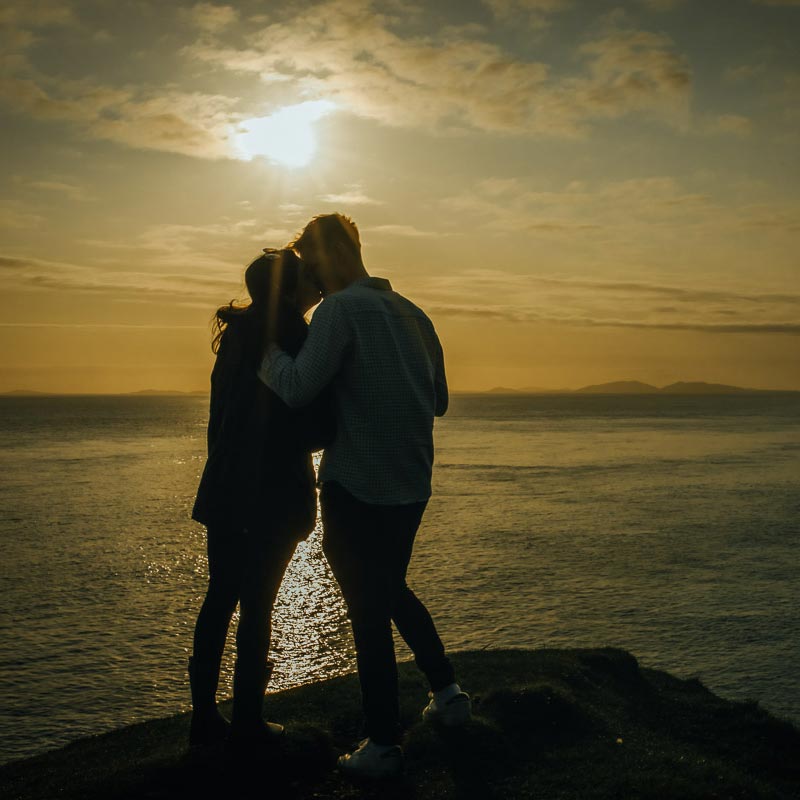 Couple kissing at sunset, on the coast, after proposing on Skye